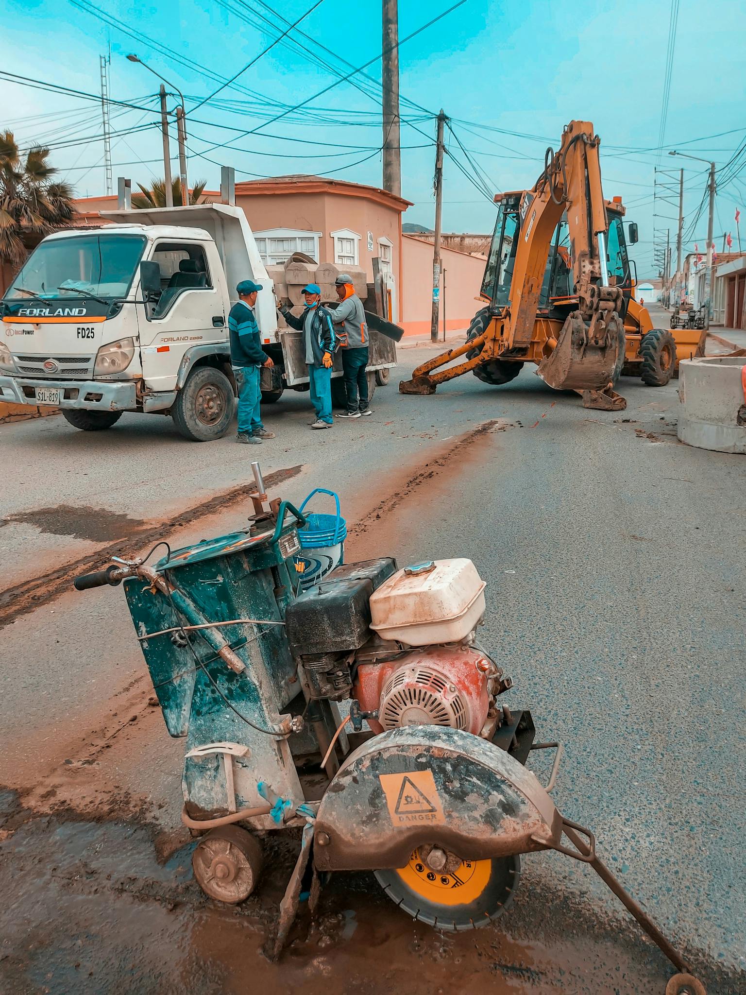 Construction site with machinery and workers repairing a road in daylight.
