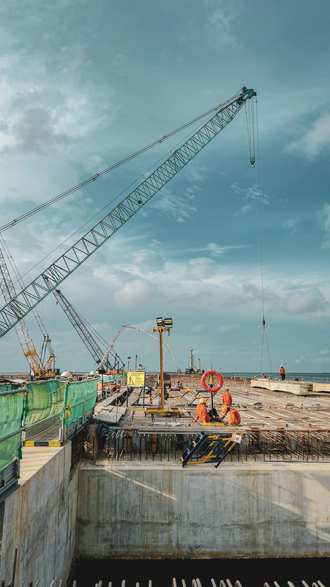 Elevated view of a construction site with cranes under a cloudy sky in West Java, Indonesia.